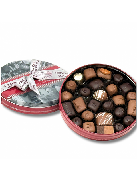 100th Anniversary LG Tin featuring an assortment of delicious chocolates from Phillips Chocolate. The tin is elegantly designed with a vintage ribbon and showcases a variety of chocolates arranged in black liners, perfect for gifting or personal enjoyment.