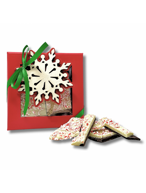 Box of Peppermint Bark by Phillips Chocolate with semi-sweet dark chocolate and white chocolate topping, festive ribbon, and holly decoration.